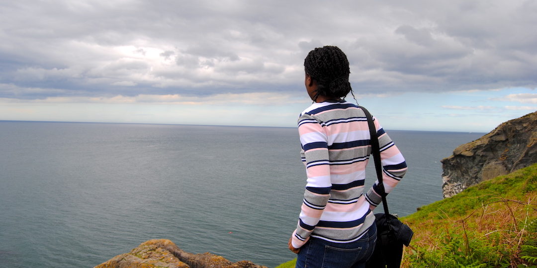 photo of a black girl on a mountain looking at the ocean