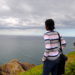 photo of a black girl on a mountain looking at the ocean